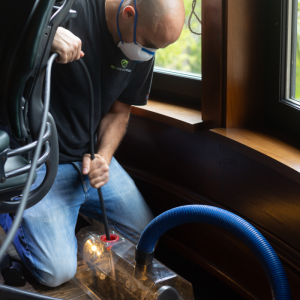 R&E Home Solutions technician cleaning a floor air duct with professional vacuum equipment.